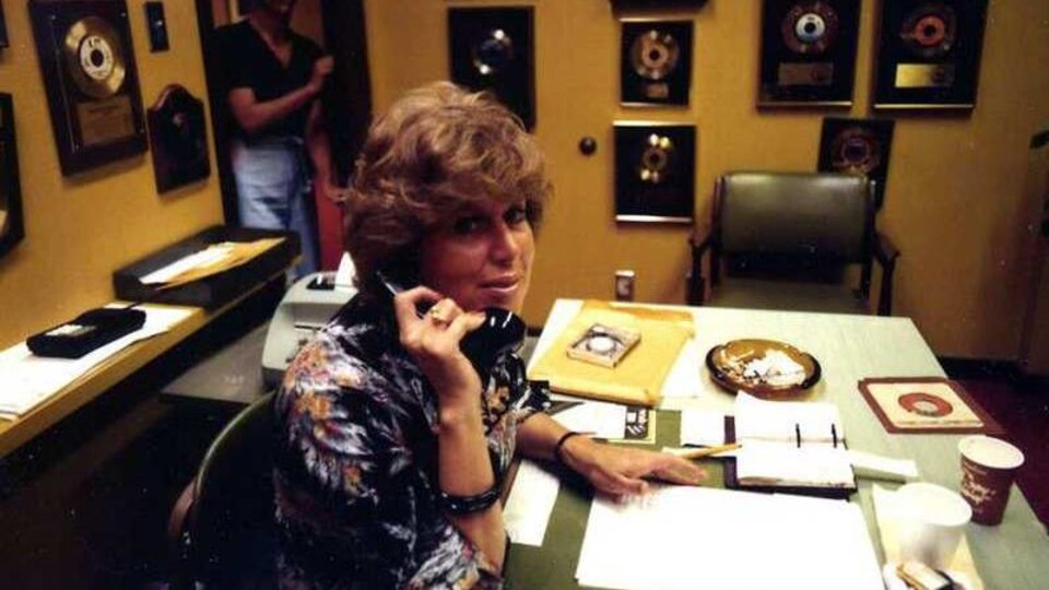 Photo d'archives des années 1970. Une femme est au téléphone dans un bureau. Des disques sont accrochés au mur