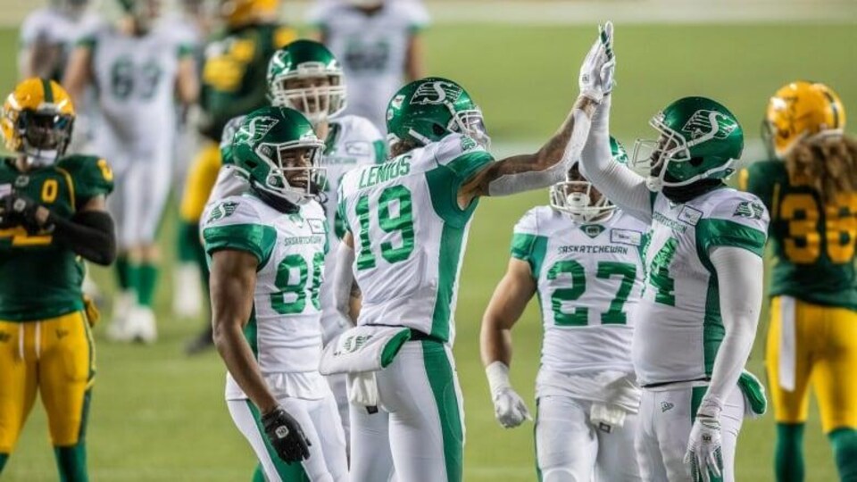 Des joueurs des Roughriders de la Saskatchewan célèbrent sur le terrain de football.