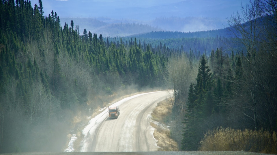 Un camion lourd circule dans les nuages de poussières sur la route 389.
