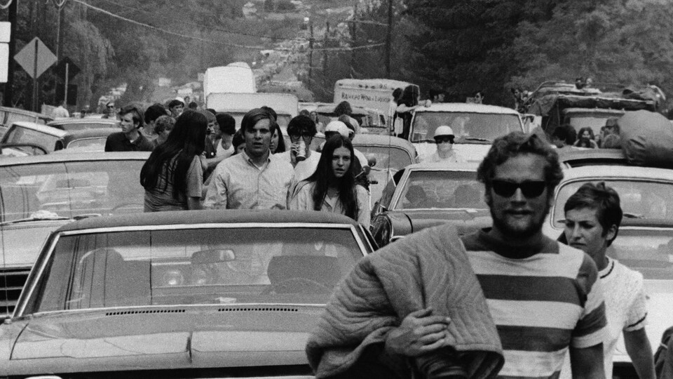 Des personnes marchent sur une route où de nombreux véhicules ont été abandonnés par leurs occupants.
