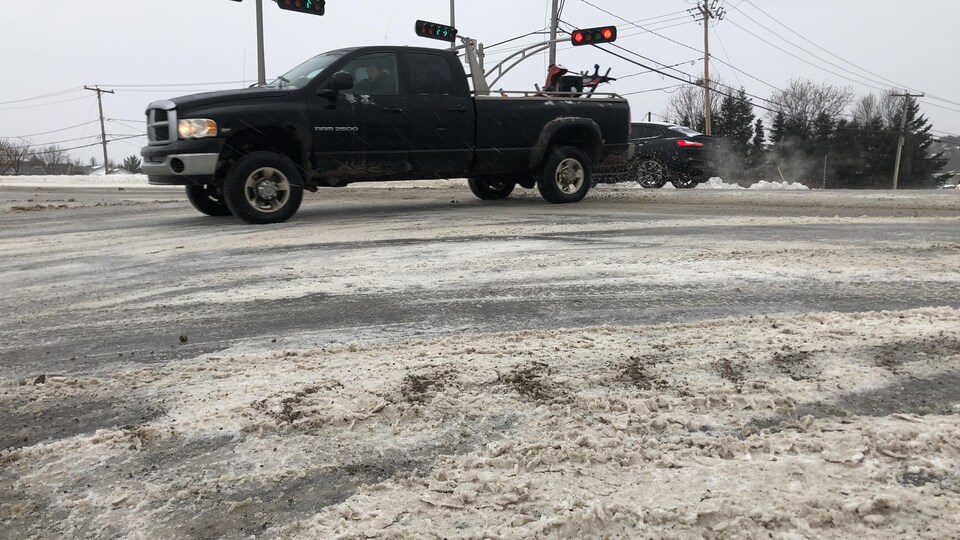 Une camionnette tourne sur une route enneigée.
