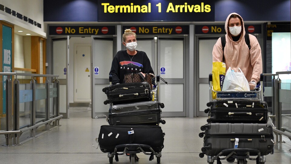 Des passagers portant un masque de protection à l'aéroport de Manchester, dans le nord de l'Angleterre.