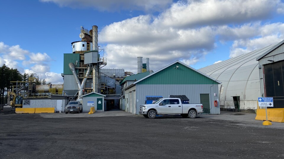 Une usine se dresse sous un ciel partiellement nuageux.