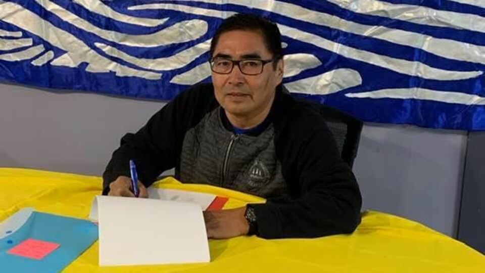 Un homme portant des lunettes qui signe un document