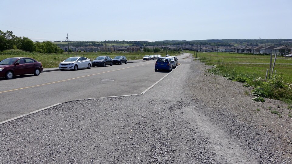 Des voitures stationnées de chaque côté de la chaussée d'une rue.