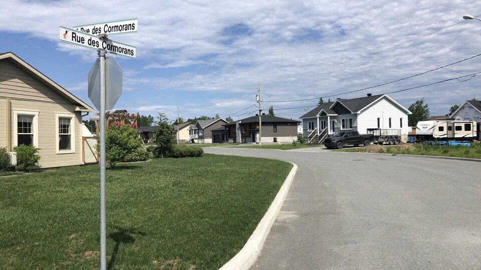 Une rue résidentielle avec l'affiche de la Rue des Cormorans.