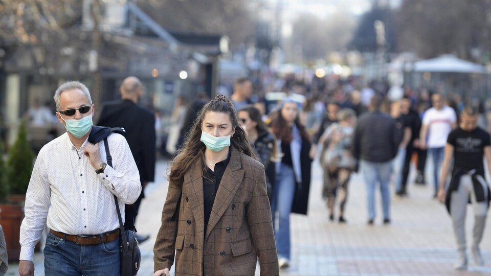 Un homme et une femme portant des masques marchent dans la rue.