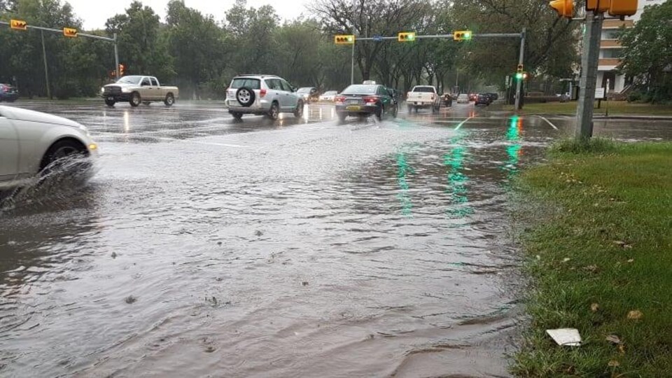 Des voitures traversent une intersection inondée à Regina.