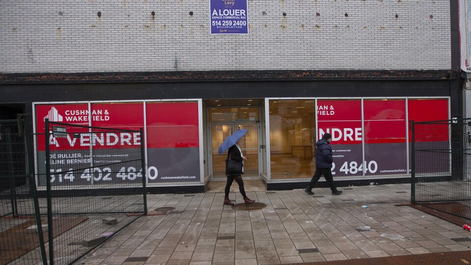 Des passants devant un commerce à vendre.