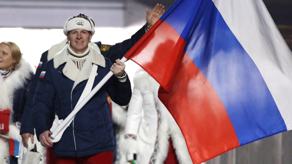 Un homme défile avec le drapeau russe aux Jeux olympiques.