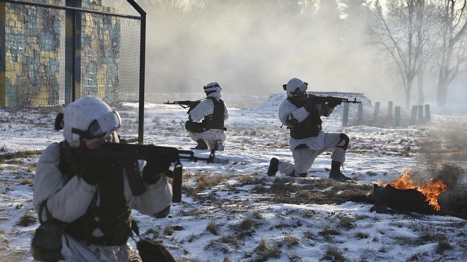 Trois soldats sont en position de tir dans un champ enneigé.