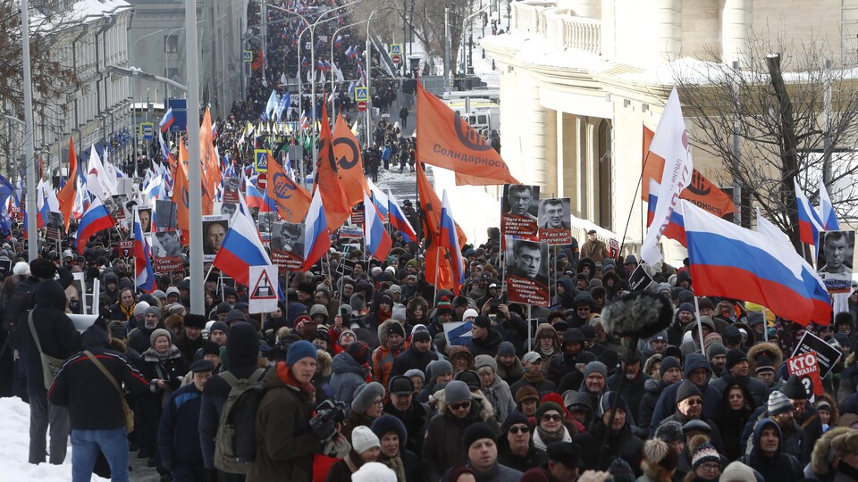 Des milliers de gens marchent dans une rue de Moscou, drapeaux à la main.