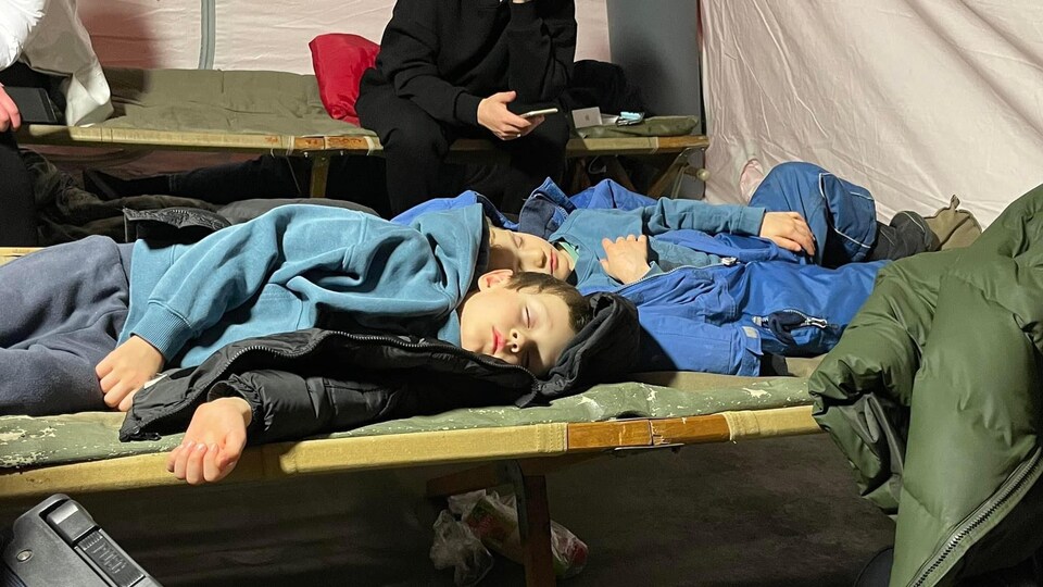 Des garçons âgés de 4 et 6 ans sont couchés sur un lit de camp dans un abri souterrain.