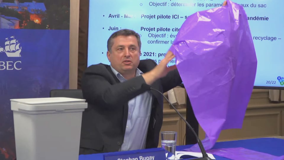 Le directeur de la gestion des matières résiduelles à Québec tient un grand sac de plastique mauve dans ses mains.