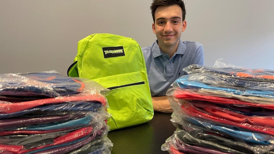 Paul Drakos devant des dizaines de sacs à dos.