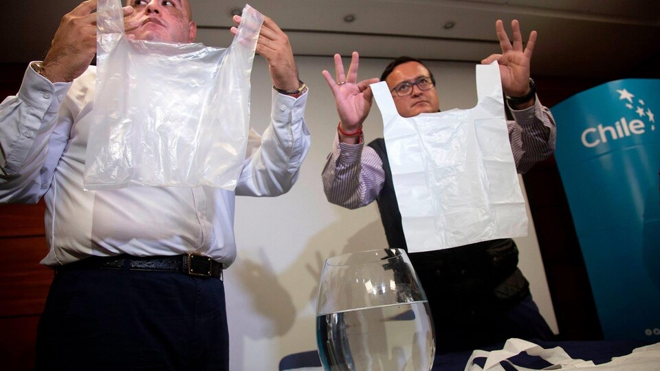 Deux chercheurs brandissent leurs sacs fabriqués à base de calcaire devant un verre d'eau.