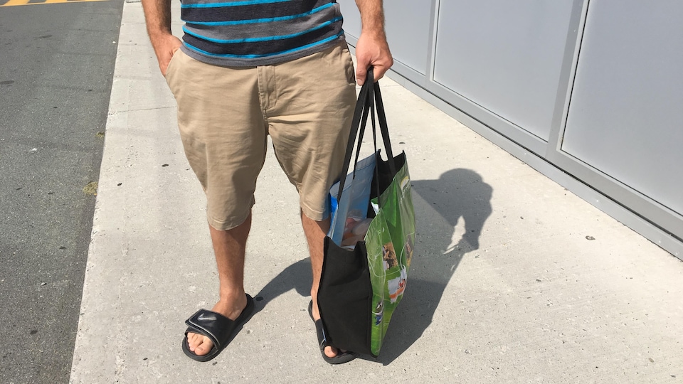 Un homme tient un sac réutilisable rempli de ses achats chez IGA.