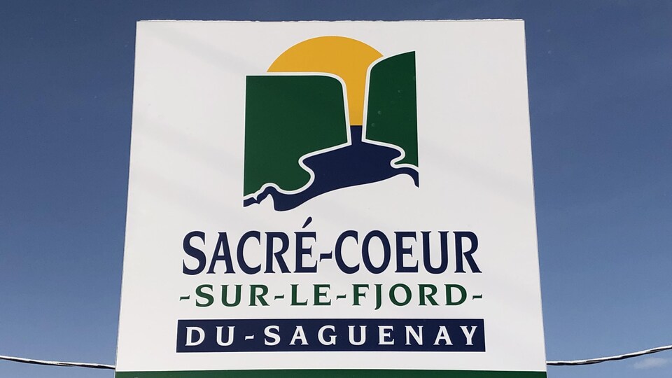 Le logo du village de Sacré-Cœur est imprimé sur un monument installé à l'extérieur.