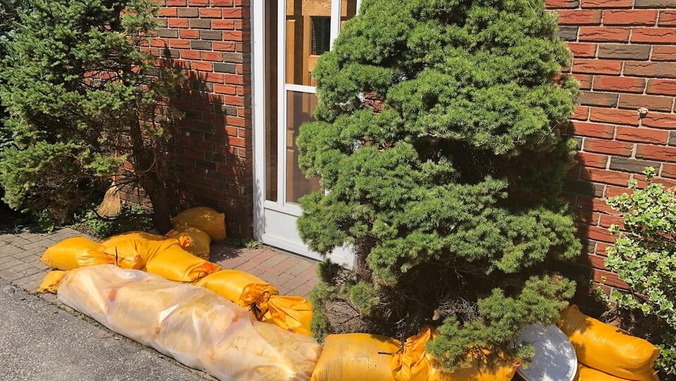 Des sacs de sable sont entassés devant une maison