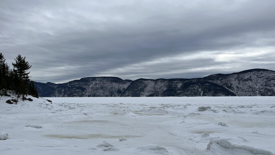 Le fjord du Saguenay avec des montagnes en arrière-plan. La rivière est glacée et recouverte de neige. 