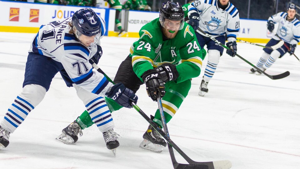Deux joueurs de hockey se disputent le disque.