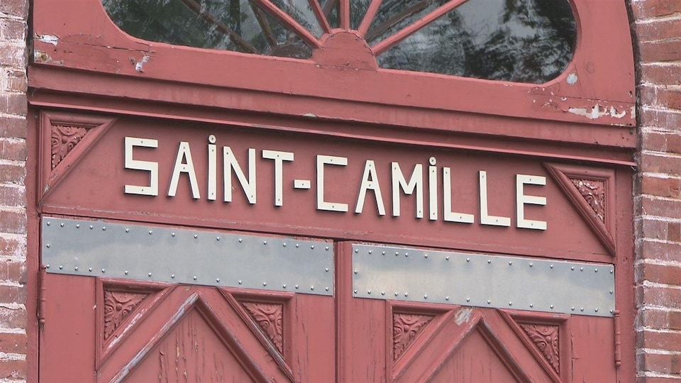 Le village de Saint-Camille est illustré par une inscription du nom du village qui figure au-dessus d'une imposante porte. 