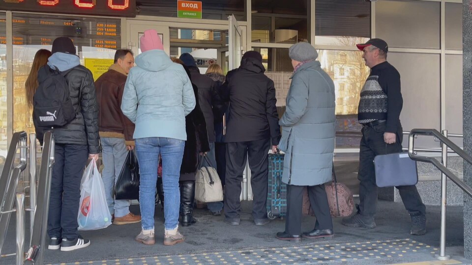 Des hommes et des femmes à l'entrée d'une gare en Russie.