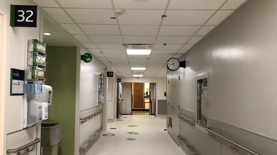 Un couloir d'hôpital dégagé, blanc et vert.