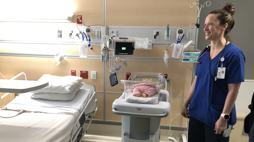 Une chambre d'hôpital avec un lit pour la mère et une couchette pour bébé.