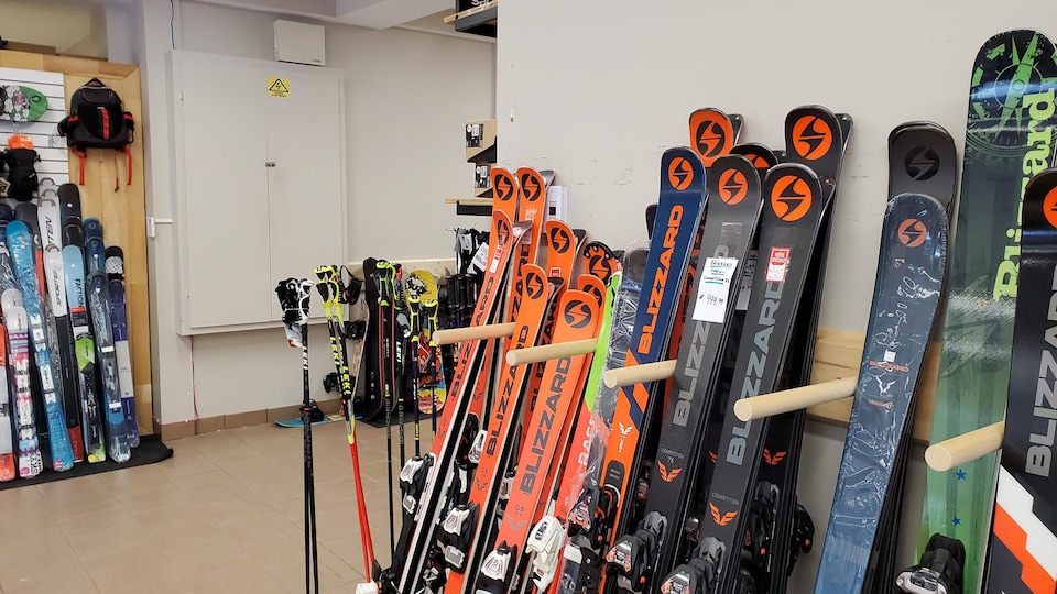 Des skis et des bâtons rangés contre un mur.