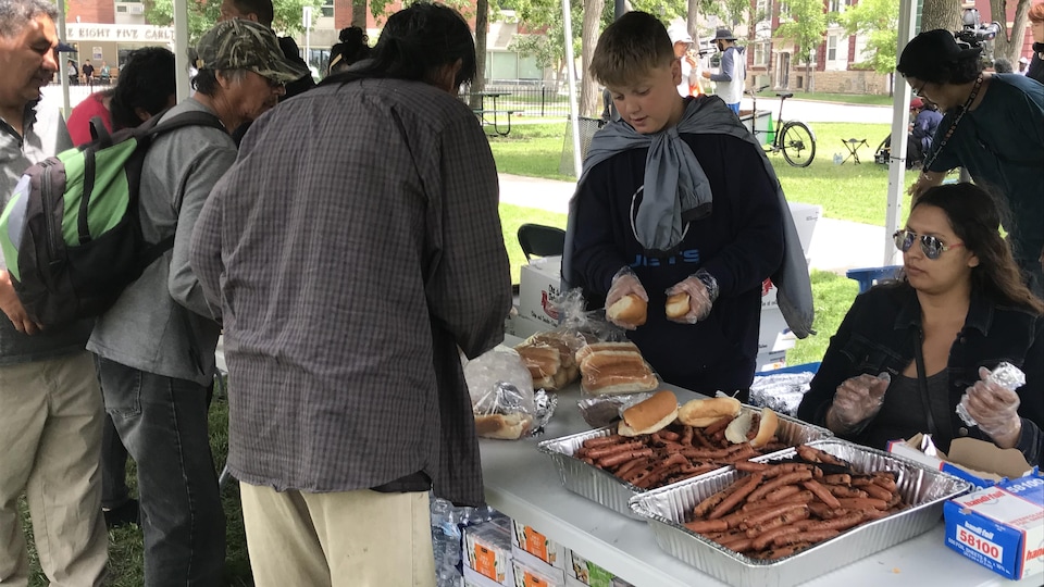 Des personnes se servent de hot-dogs le 25 juin 2022 à Winnipeg.