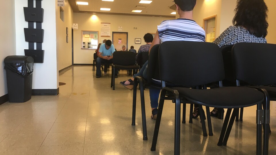 Des gens qui attendent assis dans une salle.