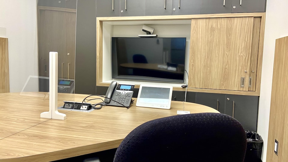 A telephone was placed on a table.  A screen is attached to the wall.