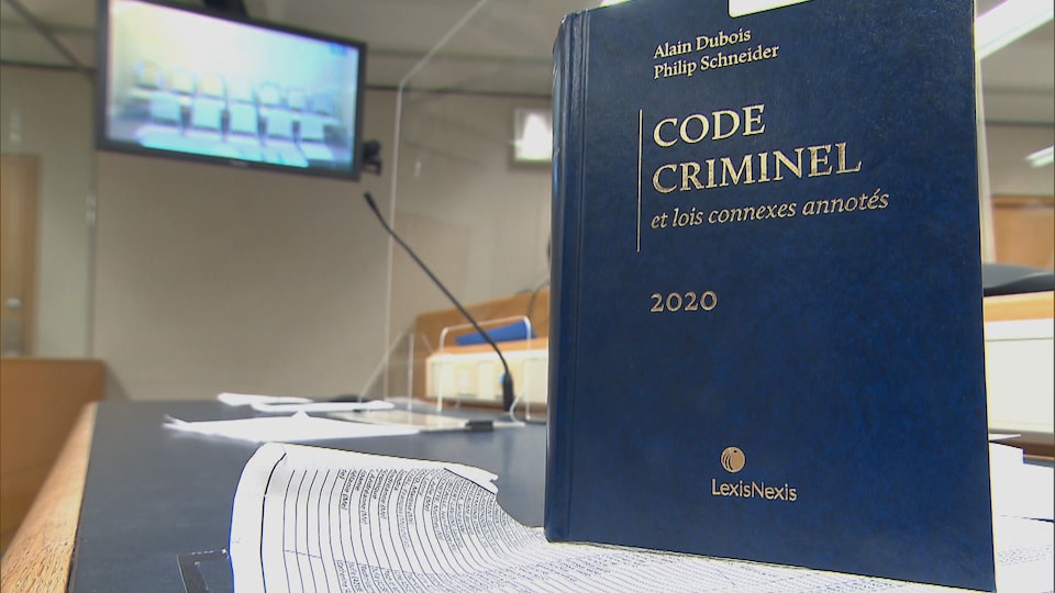 Un code criminel en avant plan, dans une salle d'audience