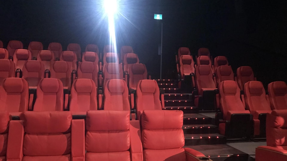 Une salle de cinéma dotée de fauteuils rouges.