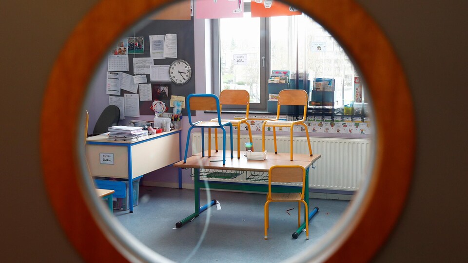 Une salle de classe vide photographiée à travers l'œil magique d'une porte.