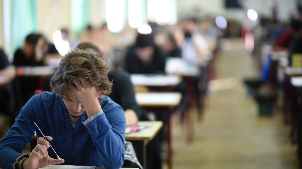 Un adolescent est penché sur son bureau dans une salle de classe.