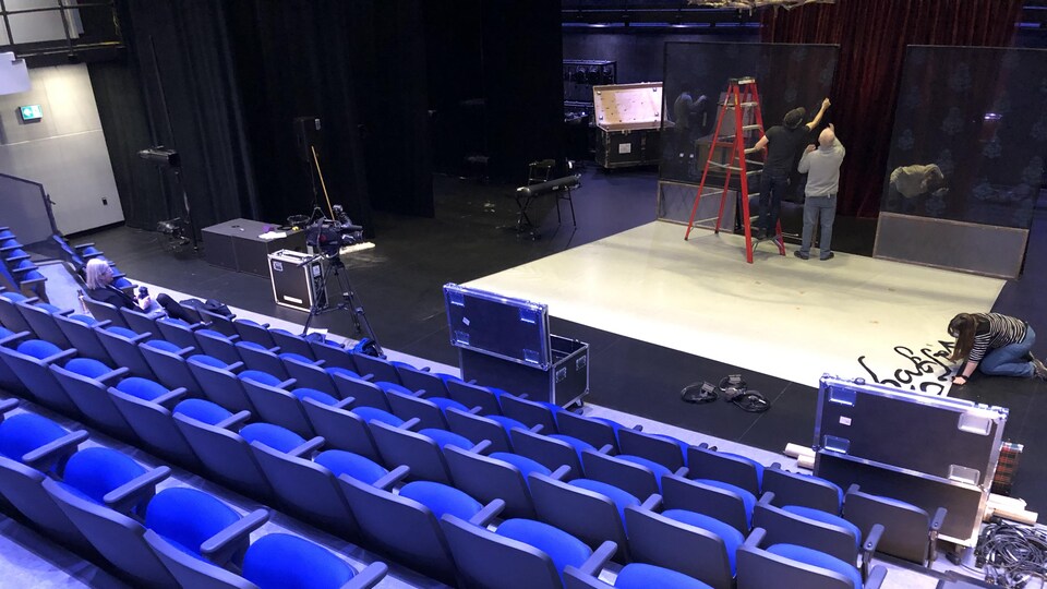 Des techniciens installent des décors sur la scène.