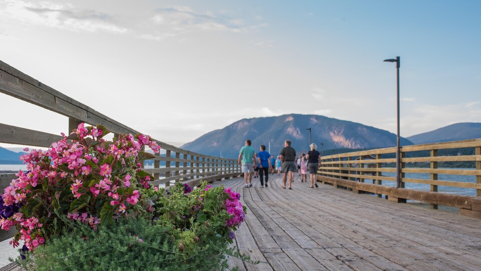 Un quai en bois avec des personnes dessus, une montagne en face.