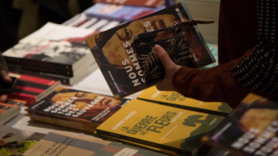 Des livres posés sur une table, et une main qui tient un livre.