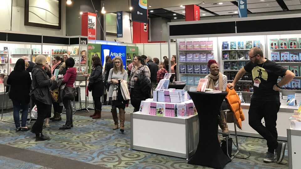 Des gens marchent dans un salon du livre.