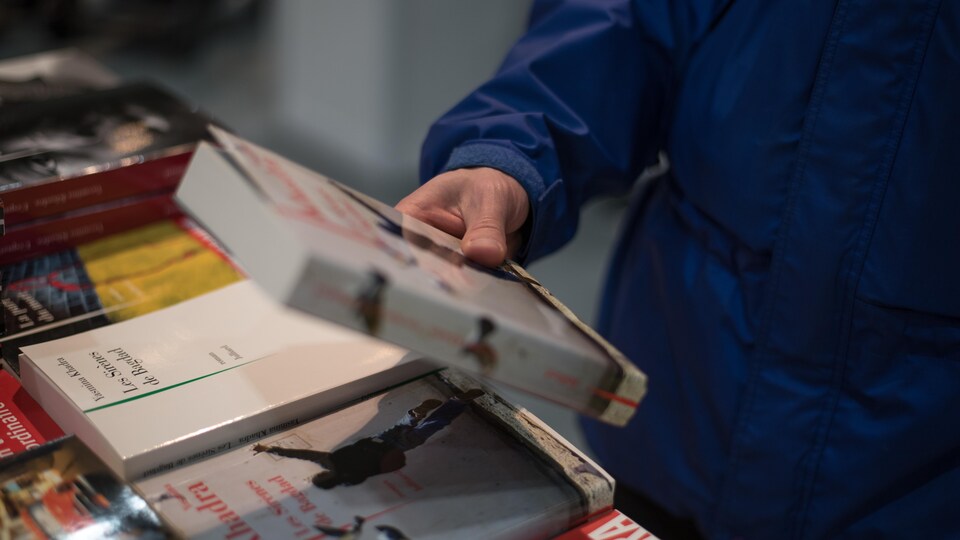 Une personne tient un livre dans sa main lors du Salon du livre de Québec.