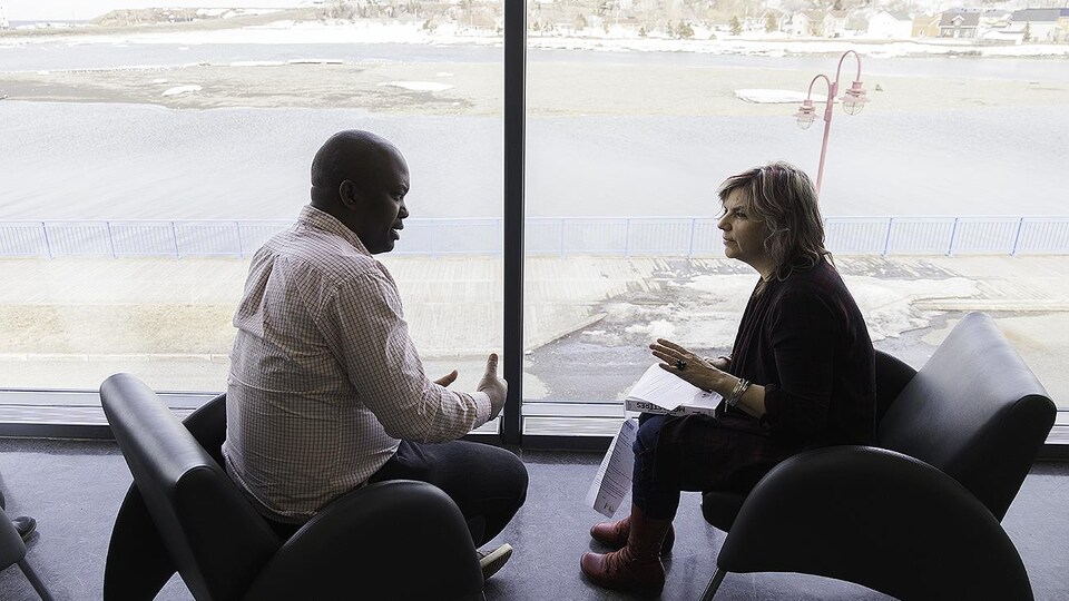 Un homme noir discute avec une femme blanche à la Bibliothèque de Matane.