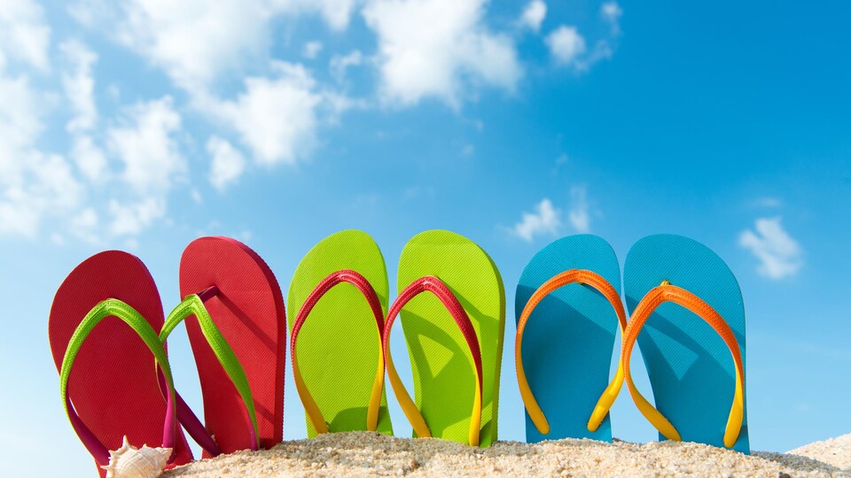 Des sandales apparaissent au sommet d'un petit monticule de sable.