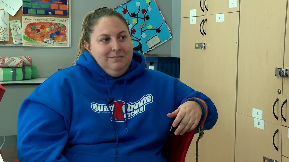 Sandra Tremblay assise sur une chaise devant des armoires dans une salle de classe.