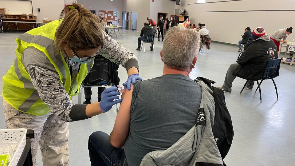 Des gens de dos qui se font vacciner.