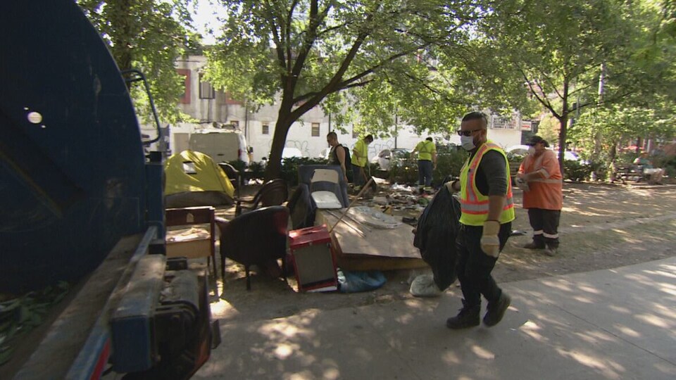 Des agents municipaux nettoient le parc après  que les campements de sans-abri eurent été retirés.