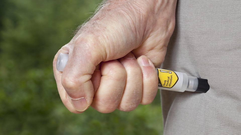 Une personne utilise un auto-injecteur EpiPen.