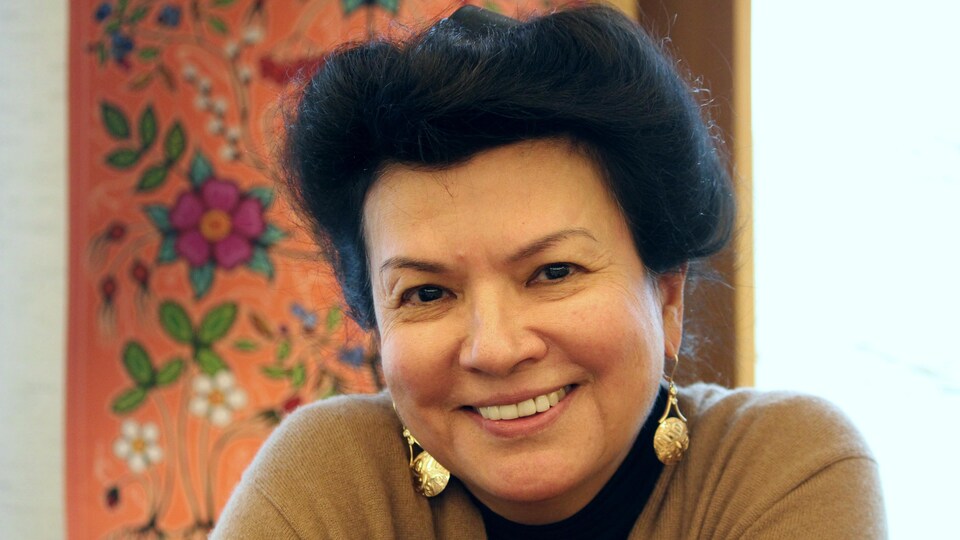 Director of Wabano Aboriginal Health Center, Allison Fisher with a painting of an Aboriginal artist in the background