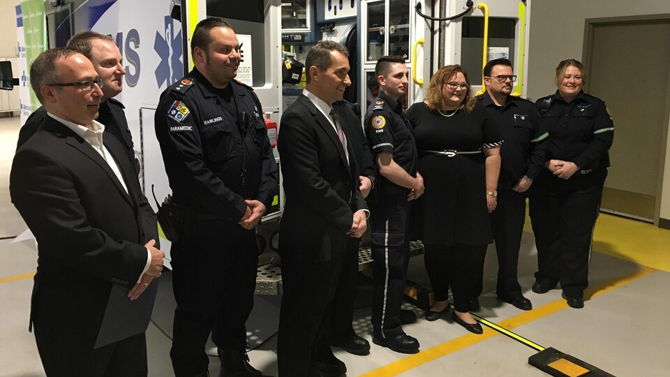 La ministre de la Santé, Sarah Hoffman, entourée d'ambulanciers devant une ambulance.